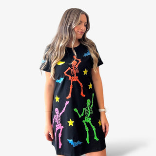 Woman wearing a black dress with colorful skeleton designs on a white background