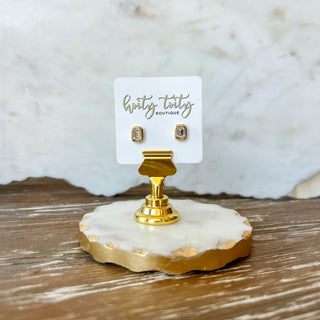 Gold stud earring on a white card with 'hotiy toity boutique' branding, displayed on a marble stand.