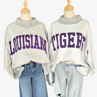 Reversible mockneck sweatshirt in gray with bold purple Louisiana and Tigers lettering, styled with jeans for a cozy game day look.