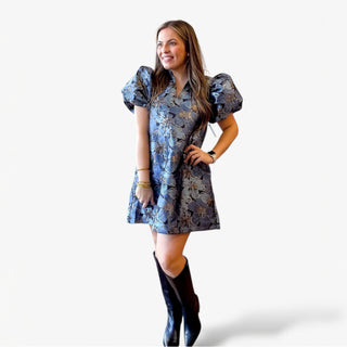 Blue floral jacquard mini dress with puff sleeves modeled on a woman wearing black boots against a clean white background.