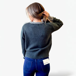 Person wearing a dark green sweater and blue jeans on a white background