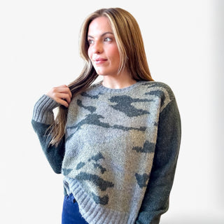 Woman wearing a camouflage-patterned sweater against a white background