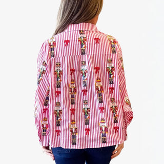 Red and white striped shirt with nutcracker pattern worn by a person on a white background