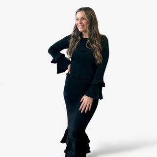 Woman wearing a black set with ruffled details on a white background