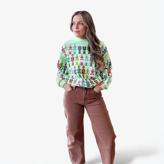 Woman wearing a colorful sweater with a pattern and brown pants on a white background
