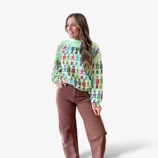 Woman wearing a colorful sweater with a pattern of small figures on a white background