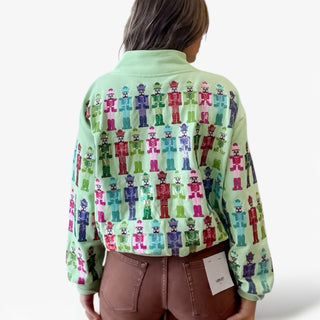 Person wearing a light green shirt with colorful nutcracker pattern on a white background