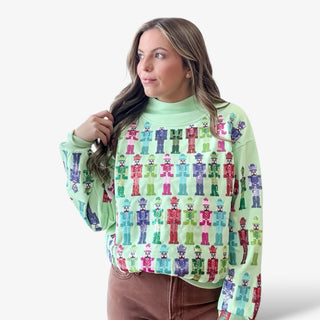 Woman wearing a green sweater with colorful nutcracker pattern on a white background