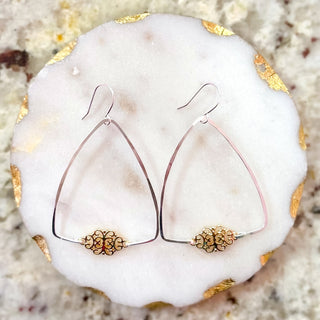 Pair of gold and silver earrings on a white stone surface