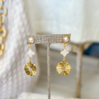 Gold pearl sunburst drop earrings with organic pearl accent displayed on neutral jewelry stand