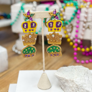 Colorful crown-shaped earrings on a stand with a blurred background