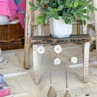 White floral earrings on a wooden chair with a blurred background