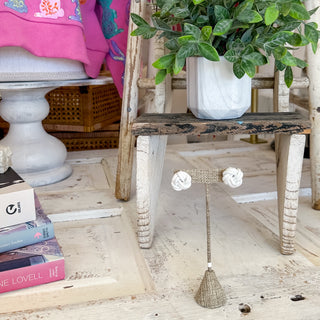 Pair of white earrings on a stand with a wooden floor background