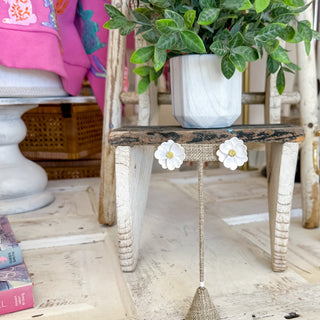 White floral earrings on a wooden chair with a blurred background