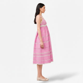 Woman wearing a pink dress with white trim on a white background