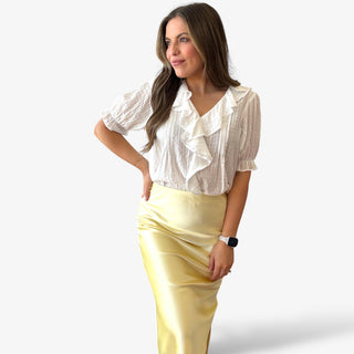 White ruffle v neck blouse with short sleeves and ruffle detailing  worn with a butter yellow satin slip skirt.