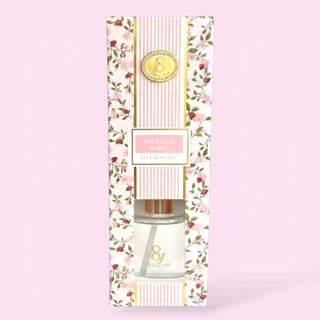 Decorative reed diffuser packaging with floral design on a pink background