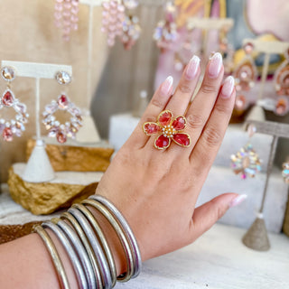 Pink flower statement ring on hand with gold detailing and crystal petals styled with silver bangles boutique jewelry front view
