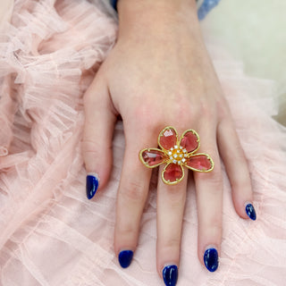 Pink flower cocktail ring with oversized crystal petals styled on hand over blush tulle fashion jewelry lifestyle view
