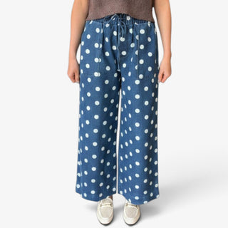 Blue polka dot denim wide leg pants with white dots, elastic drawstring waist and front patch pockets, up close view