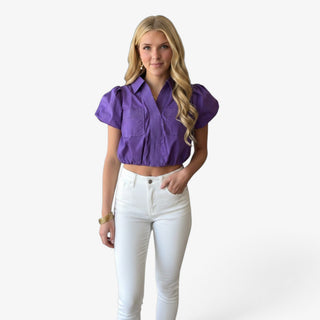 Model wearing a purple game day cropped shirt with puff sleeves, chest pockets and detailed contrast topstitching with white jeans