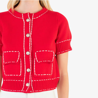 Red cardigan with white stitching and buttons on a white background