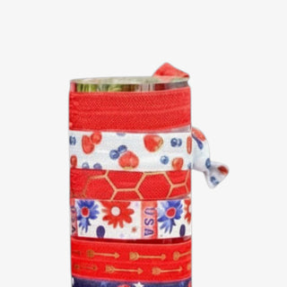 Patriotic ribbon hair ties featuring red elastic bands with gold arrow details, floral Americana prints, and red white blue cherry summer patterns