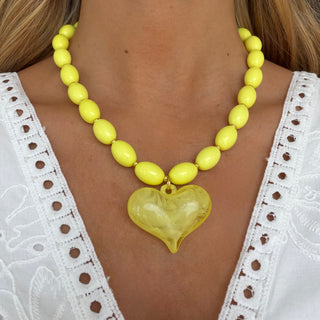 Yellow heart pendant necklace with marbled yellow beads worn by model front view