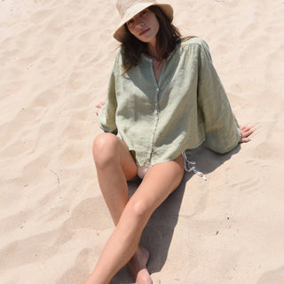     Sage linen blouse with shell buttons and oversized sleeves full body beach view