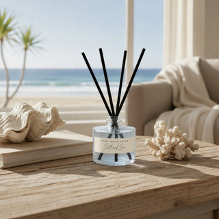 Powder blue Salt and Sea reed diffuser styled on rustic wood table with coastal decor and oceanfront living room background