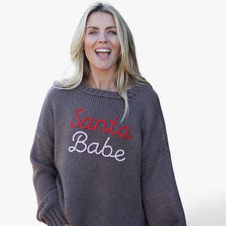 Woman wearing a sweater with 'Santa Babe' text on a plain background