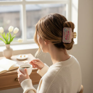 Sardine hair claw clip with pink fish design styled in a brunette updo, indoor lifestyle view near a sunny window