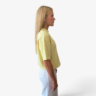 A woman in profile wearing a scuba stripe yellow short-sleeve knit top in a side view