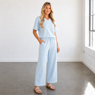 Blue scuba wide leg pants with drawstring waist and pockets styled with matching V-neck top, angled front view
