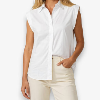 Woman wearing a tailored white cap sleeve blouse and beige pants on a white background