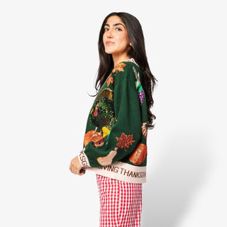 Woman wearing a green sweater with Thanksgiving-themed designs on a white background