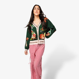 Woman wearing a festive green sweater with Thanksgiving designs on a white background