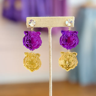 Alt Text:
Purple and gold tiger acrylic drop earrings with crystal stud posts featuring layered LSU-inspired tiger head charms, displayed on a neutral earring stand, front view.