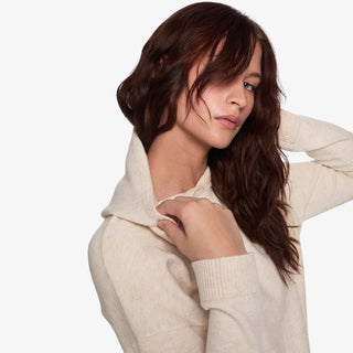Woman wearing a soft cream sweater hoodie with relaxed fit and lightweight knit design.