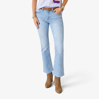A model wearing light-wash blue cropped flare jeans with a brown leather belt, paired with a striped top and brown ankle boots, against a light gray studio background.