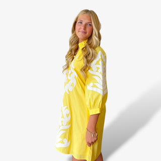 Yellow appliqué mini dress with white embroidered detailing modeled angled front view