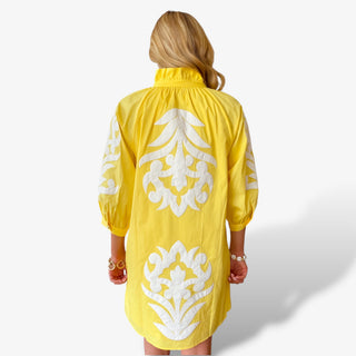 Yellow appliqué mini dress with white embroidered back detailing modeled back view