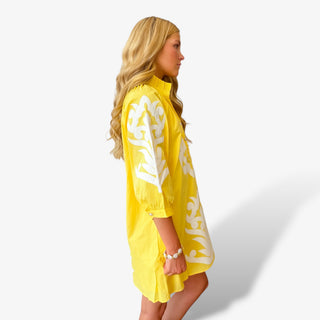 Yellow appliqué mini dress with white embroidered sleeve detail modeled side view