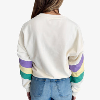Mardi Gras stripe sweatshirt with purple green and gold sleeve details on a cream crewneck top