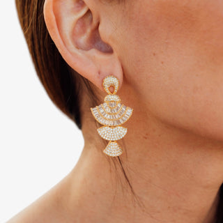 Gold crystal tiered statement dangle earrings with baguette and pave stones worn on model