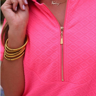 Hot pink textured zip front dress with gold zipper neckline and pockets styled outdoors front view