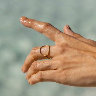 Gold wave ring on finger close-up side profile view