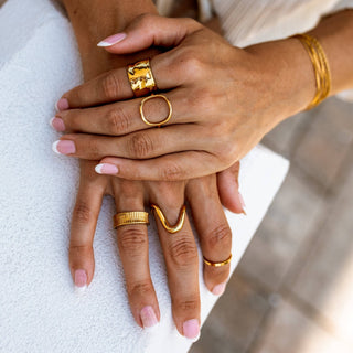 Gold statement wave ring stacked with other gold rings on model hand