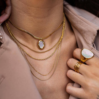 Gold mother of pearl pendant necklace styled with layered chains close-up