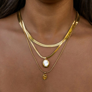 Gold herringbone necklace with mother of pearl pendant layered with chains